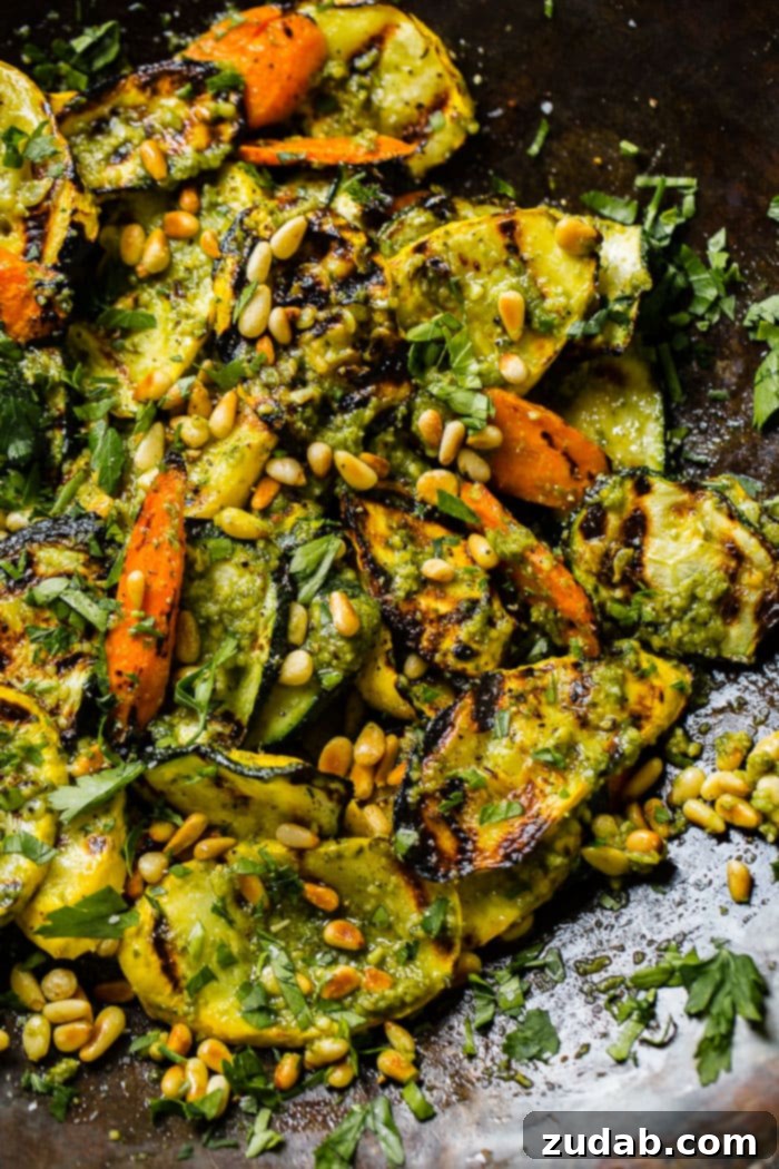 Easy 15-Minute Pesto Grilled Veggies 5 A close up of grilled veggies with pesto, parsley and toasted pine nuts including zucchini, yellow squash and carrots for a 15 minute grilled veggies with pesto recipe