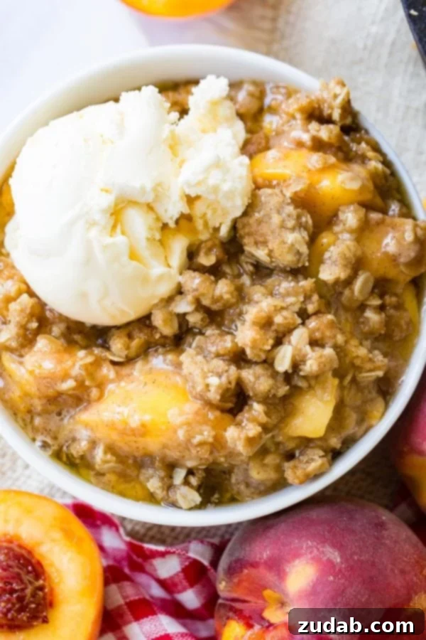 Peach Crisp A photo of a bowl of peach crisp with a scoop of vanilla ice cream on top.
