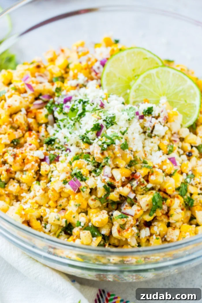 Grilled Elote Corn Salad 2 A vibrant glass bowl generously filled with a mouth-watering Grilled Mexican Corn Salad, showcasing perfectly charred corn kernels, thinly sliced red onions, fresh green cilantro, creamy Mexican crema, crumbled cotija cheese, and a glistening drizzle of lime juice, ready to be served at a summer barbecue.