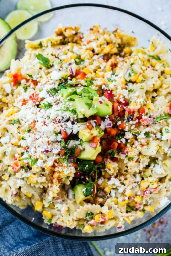 Mexican Street Corn Pasta Salad 2 A close up photo of a bow tie pasta salad with avocados, peppers, grilled corn, cilantro, and cotija cheese making up an Elote Mexican Corn Pasta Salad