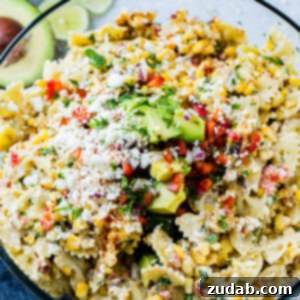 Mexican Street Corn Pasta Salad 5 A close up photo of a bow tie pasta salad with avocados, peppers, grilled corn, cilantro, and cotija cheese making up an Elote Mexican Corn Pasta Salad