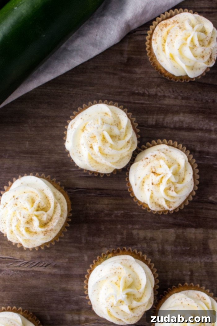 Cream Cheese Frosted Zucchini Delights 4 An inviting overhead shot showcasing several zucchini cupcakes, beautifully crowned with creamy cream cheese frosting and a hint of cinnamon.