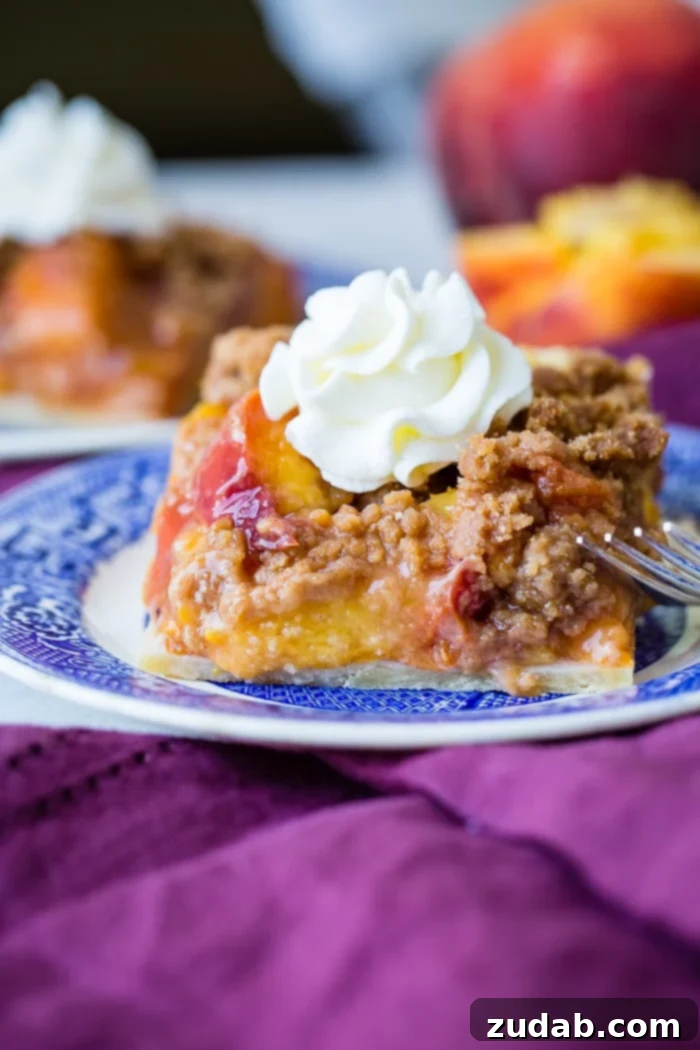 A warm, golden-brown slice of brown sugar peach pie bar, revealing its luscious peach filling, presented on a blue and white china plate.