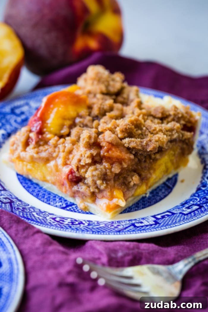 A vibrant slice of brown sugar peach pie bar, perfectly baked with a golden crumble topping, served on a blue and white china plate.
