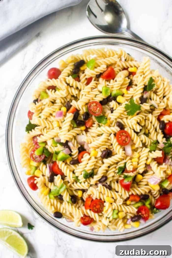 Fiesta Southwest Pasta Salad 3 A large bowl filled with colorful Mexican pasta salad, featuring a vibrant chili lime vinaigrette dressing and an abundance of fresh ingredients.