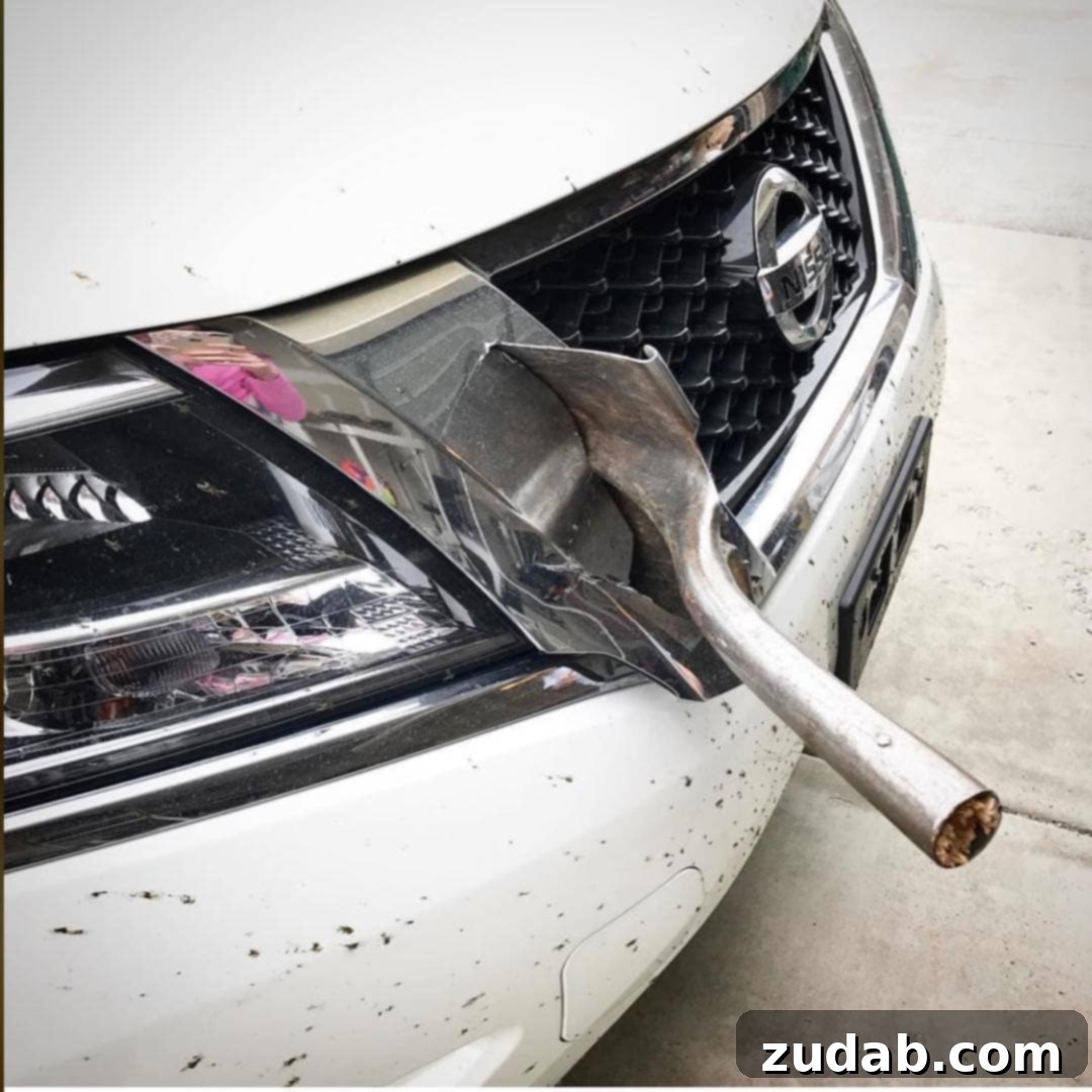 Miracle on a Handle 2 Large, jagged piece of metal impaled deeply into the front grille of a white car, demonstrating severe vehicle damage from highway debris.