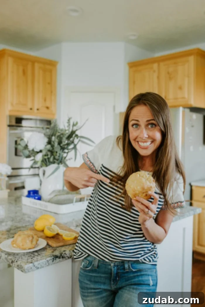Lemon Drizzle Cookies 5 carrian from ohsweetbasil.com pointing at a lemon cookie from goodly cookies