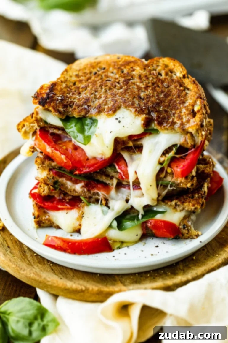Gourmet Havarti Tomato Basil Grilled Cheese 5 A photo of a stack of melty Havarti tomato basil grilled cheese sandwiches on a white plate, highlighting the rich colors and textures of the ingredients.