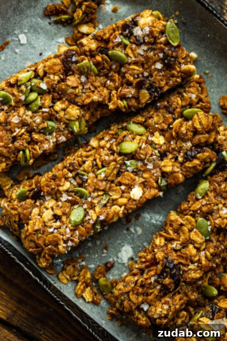 Easy Delicious Cereal Bar Recipe 3 Close-up of chewy peanut butter cereal bars on white parchment paper, showcasing the rich, binding peanut butter and mixed-in ingredients.