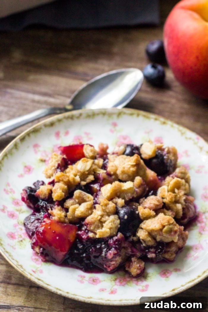 Blueberry Peach Delight 2 A vibrant plate of blueberry peach crumble, showcasing juicy, tender berries and peaches beneath a golden-brown, crunchy oatmeal topping. Ideal for a summer dessert.