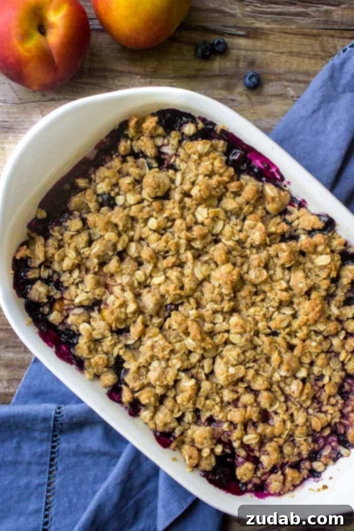 Blueberry Peach Delight 3 A beautifully baked dish of warm blueberry peach crumble, generously topped with golden-brown oatmeal and brown sugar. Perfect for a cozy dessert.