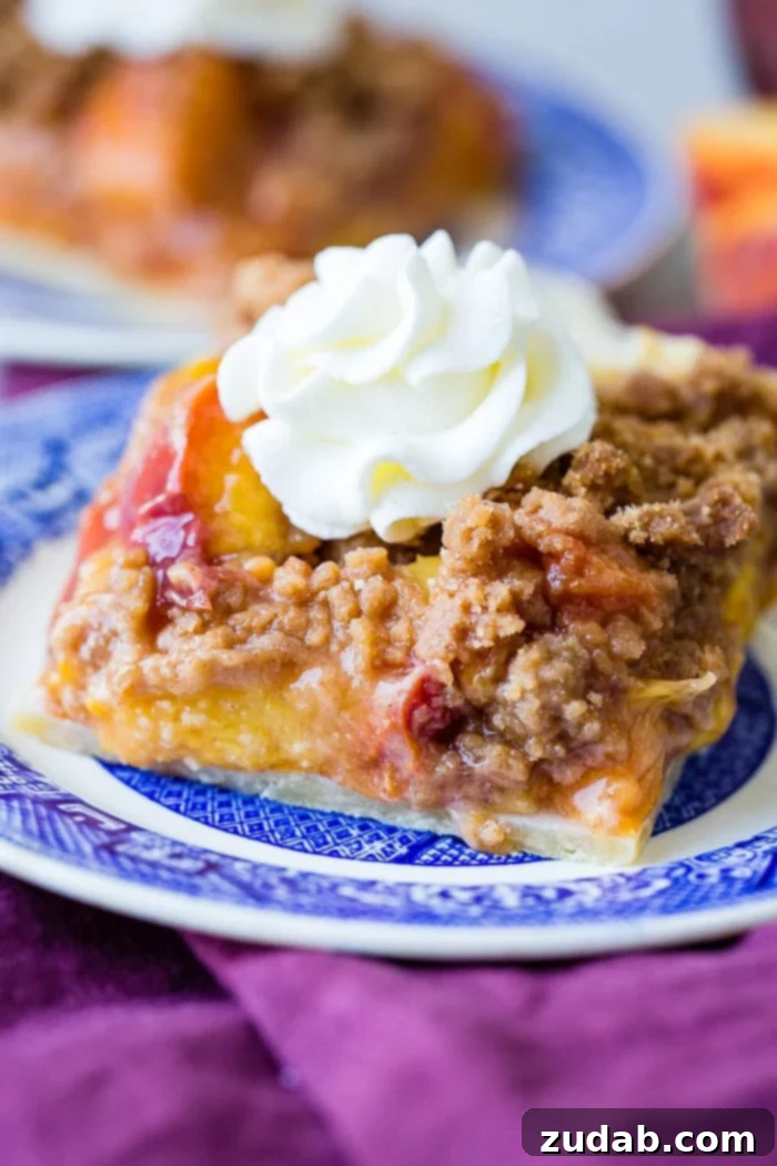 Blueberry Peach Delight 8 A purple napkin under a vibrant blue china designed dessert plate with a slice of brown sugar peach pie bars with a piped whipped cream dollop on top