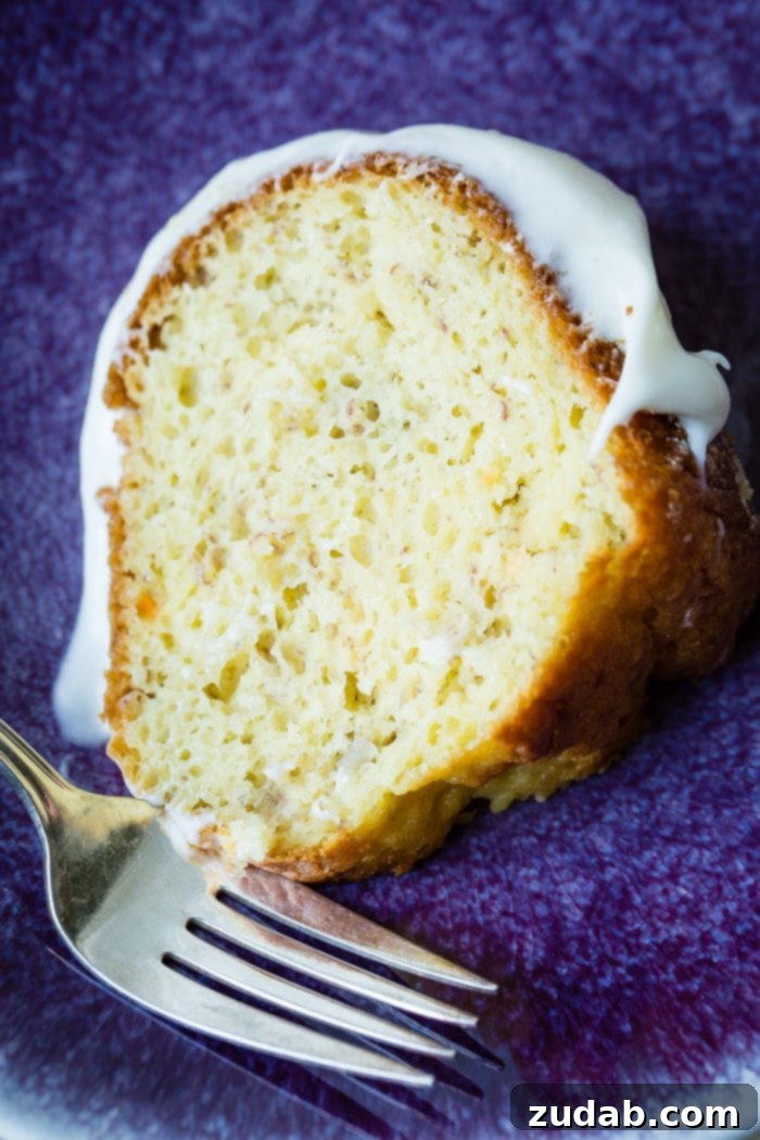 The Ultimate Banana Bundt 11 A slice of banana bundt cake with white creamy frosting on a blue plate.