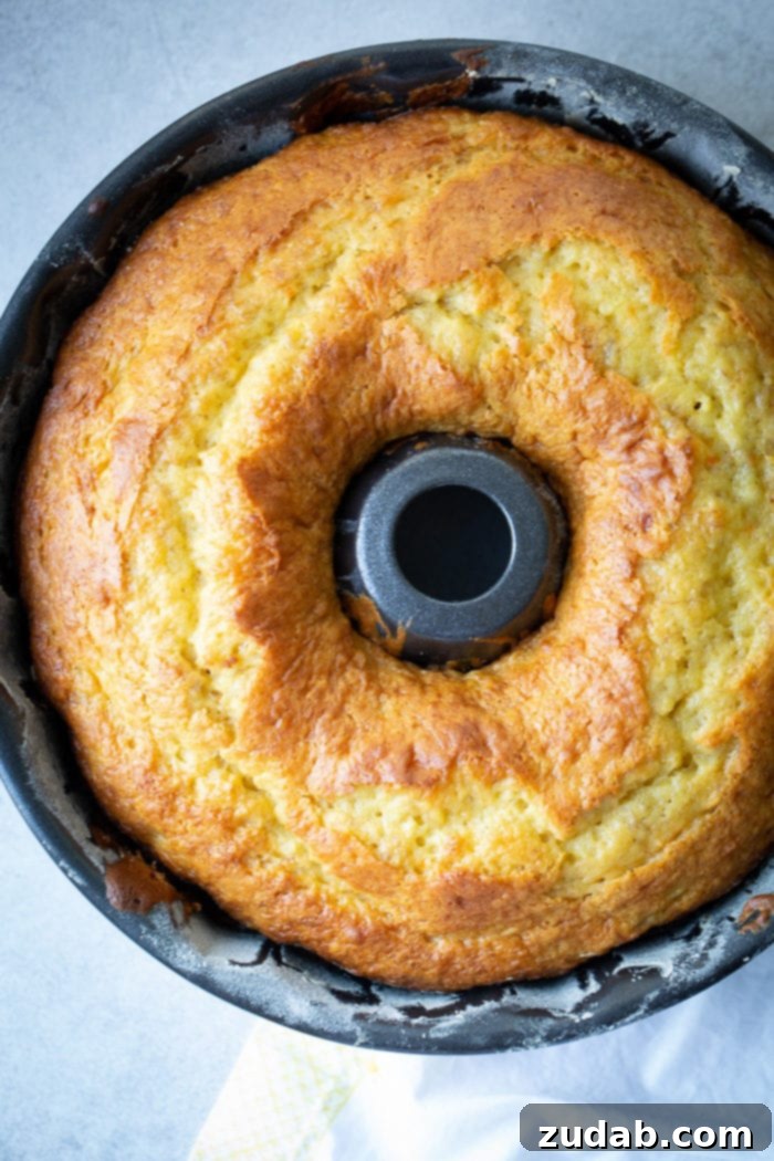 The Ultimate Banana Bundt 5 A dark bundt pan with a beautiful, bright yellow banana pudding bundt cake
