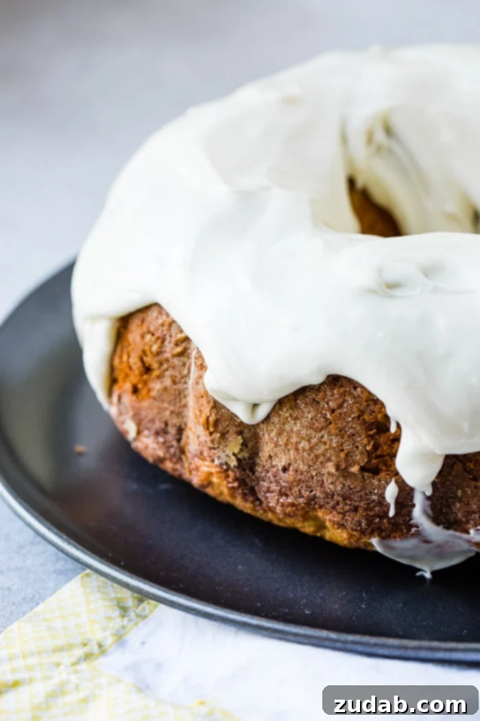 The Ultimate Banana Bundt 10 A dark grey platter with a banana pudding bundt cake slathered with cream cheese frosting