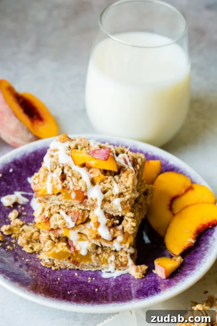 A dark purple plate with a stack of healthy peach oatmeal bars with a little glaze on top with a glass of milk behind it, emphasizing a wholesome snack