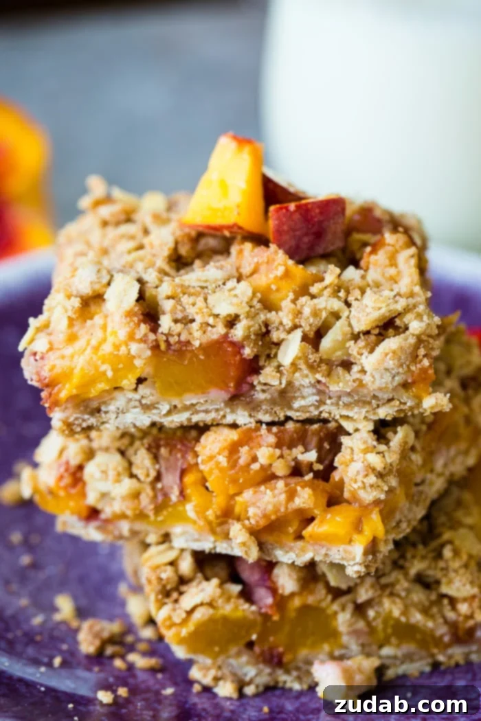 A dark purple plate with a stack of healthy peach oatmeal bars with a little glaze on top, emphasizing their appeal as a healthy snack