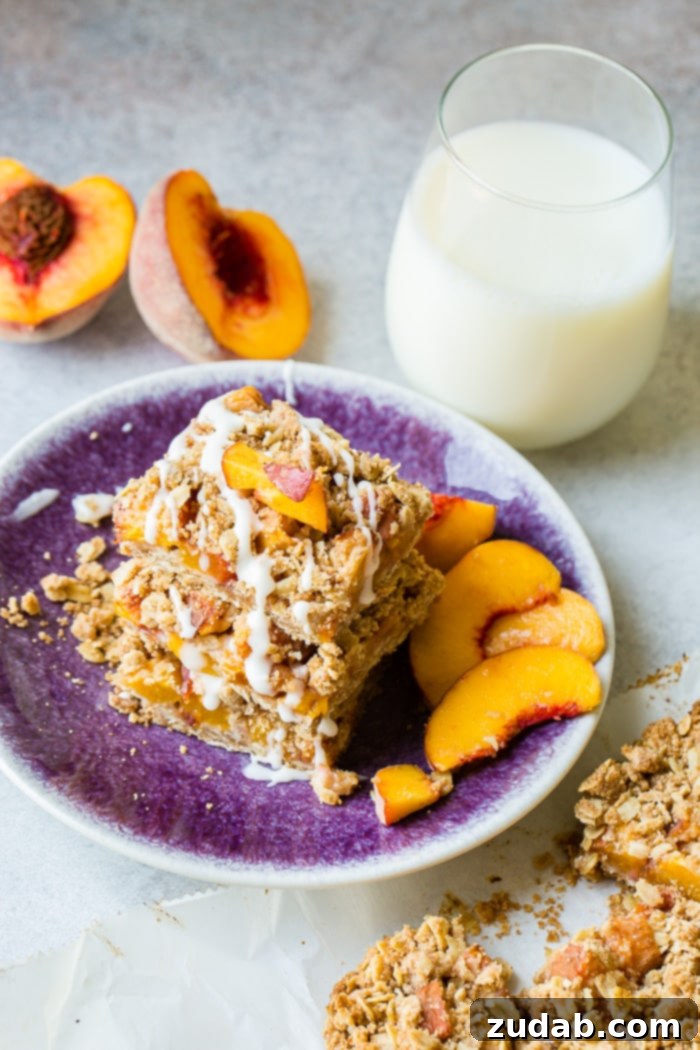 A dark purple plate with a stack of healthy peach oatmeal bars with a little glaze on top, showcasing the perfect, golden-brown bake