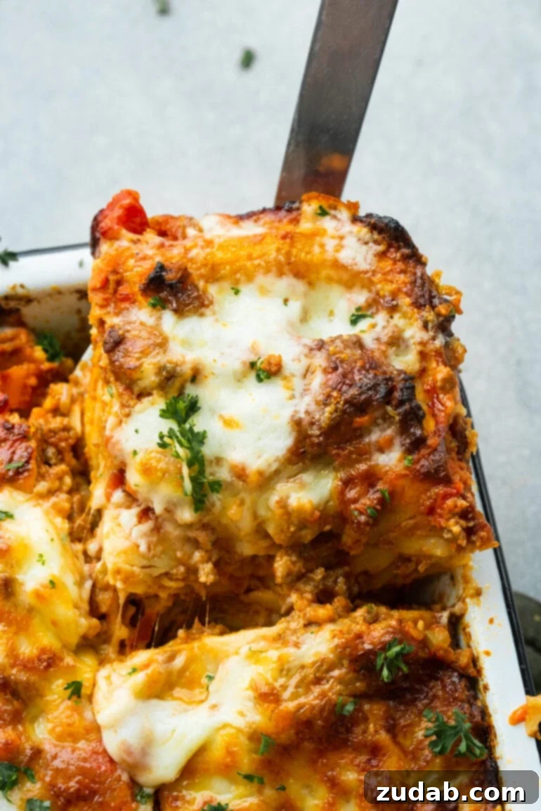 My Go-To Lasagna Masterpiece 11 A close-up of a serving of meaty lasagna being carefully lifted from the corner of a baking dish, highlighting its delicious, perfectly formed layers.