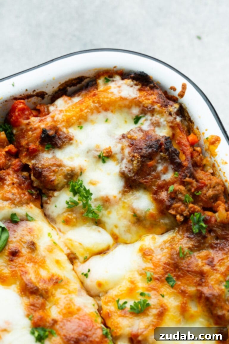 My Go-To Lasagna Masterpiece 13 A close-up shot of the corner of a baking dish filled with baked meat lasagna, featuring its perfectly layered pasta, rich meat sauce, and golden-brown melted cheese.