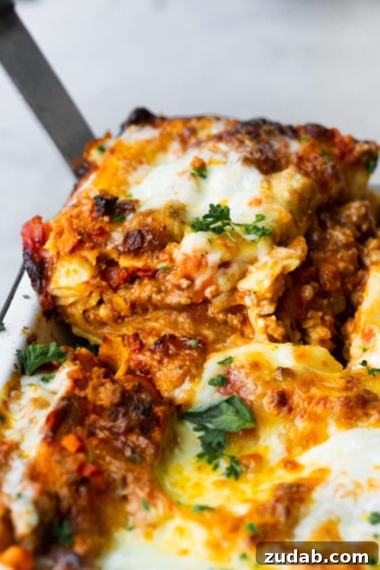 My Go-To Lasagna Masterpiece 3 A close-up photo captures a serving of homemade meat lasagna being carefully lifted from a baking pan, revealing its exquisite layers of pasta, rich meat sauce, and creamy cheese.