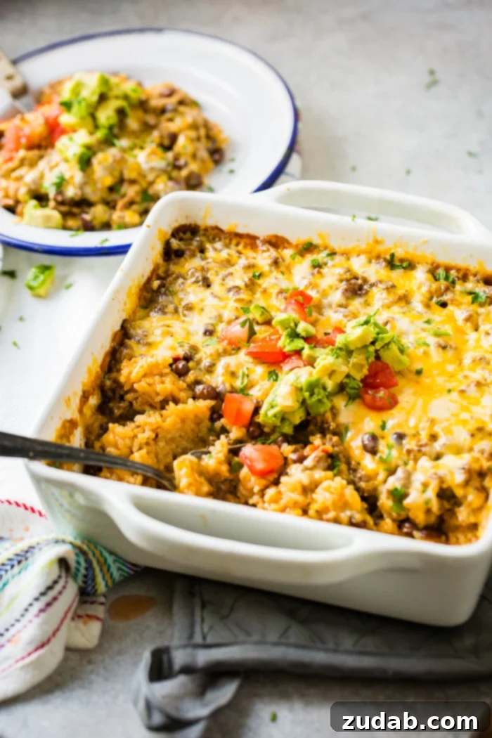 Zesty Beef and Rice Cheese Bake 6 A white casserole dish with a Mexican cheesy ground beef and rice casserole, showing its delicious layers before serving.