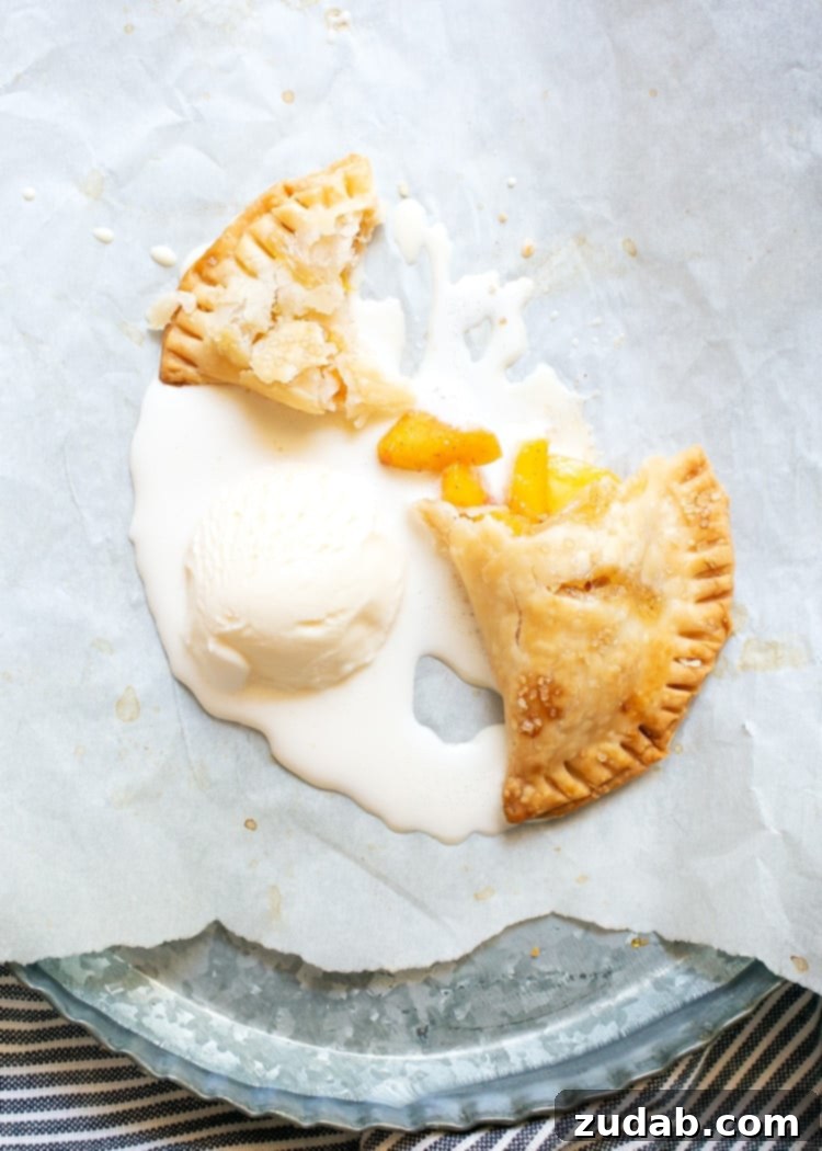 Delicious Baked Peach Hand Pies Recipe with Vanilla Ice Cream overhead view of half eaten hand pie with scoop of melting vanilla ice cream