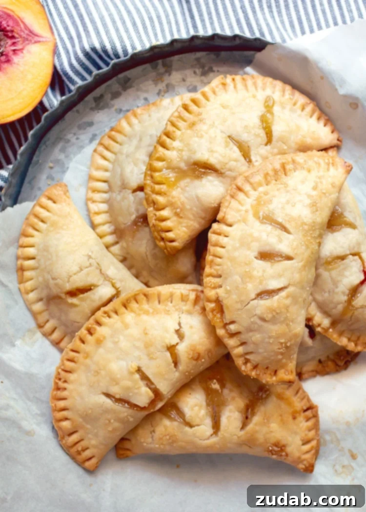 Homemade Peach Hand Pies on a Baking Tray overhead view of pile of peach hand pie on metal tart pan