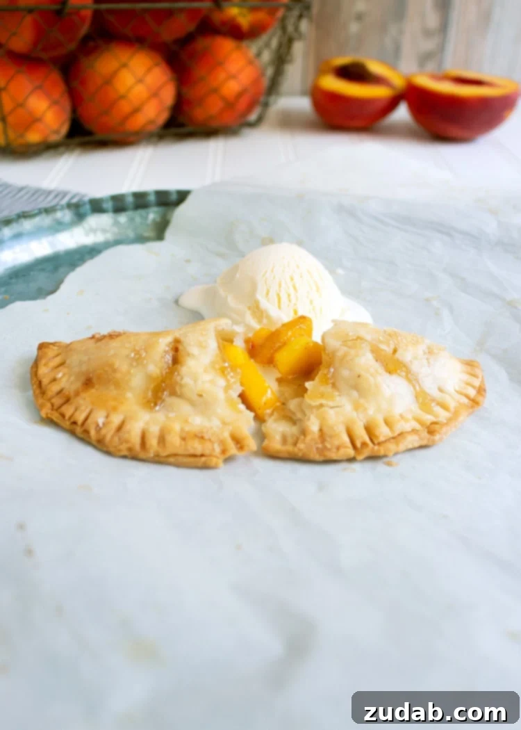 Perfectly Baked Peach Hand Pie with Ice Cream side view of peach hand pie that's been broken in half and topped with vanilla ice cream