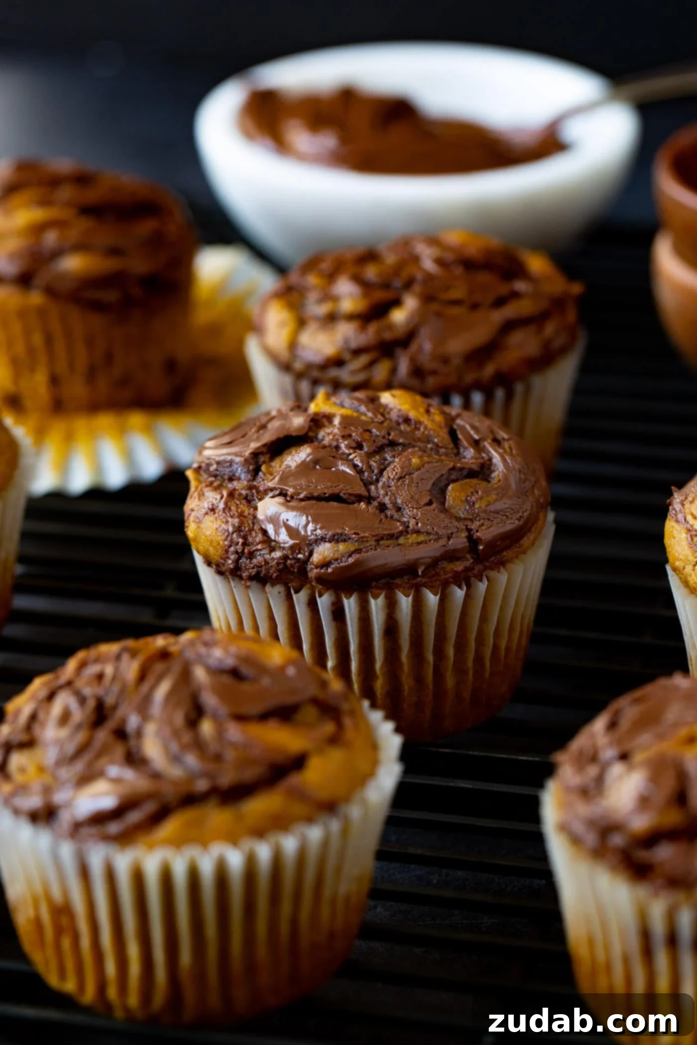 Nutella Swirled Pumpkin Muffins Nutella swirled pumpkin muffins. The paper liner has been peeled back on one muffin so you can see the pumpkin with the nutella swirled in it.