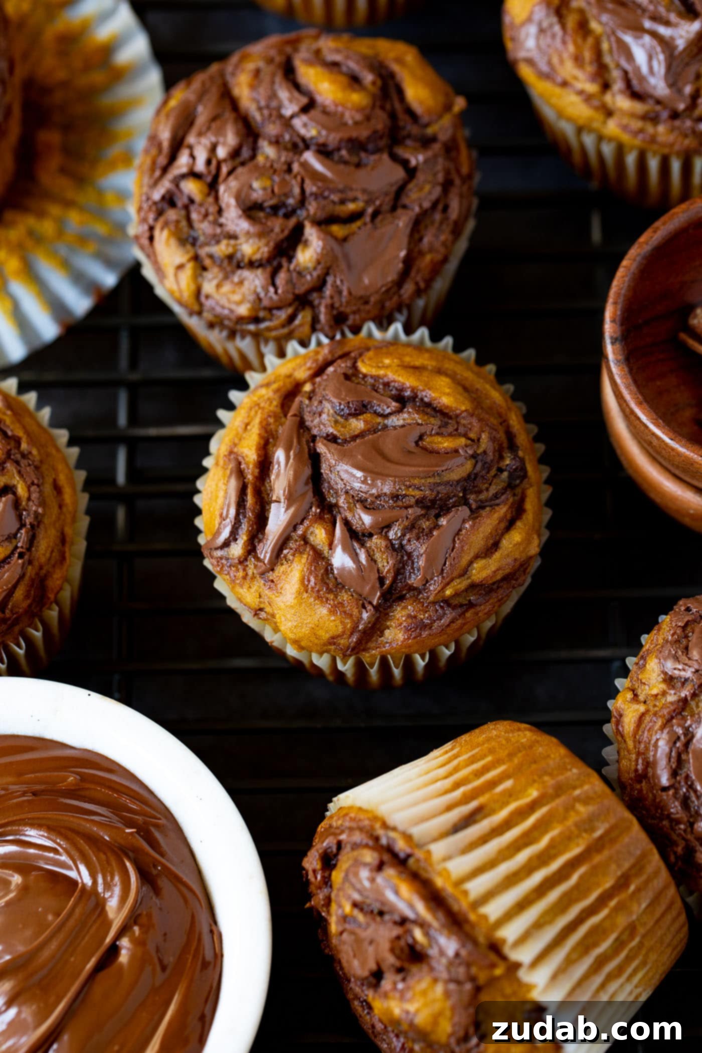 Nutella Swirled Pumpkin Muffins Nutella swirled pumpkin muffins. Nutella has been swirled through the muffin before being baked. A small bowl of Nutella sits next to the muffins.