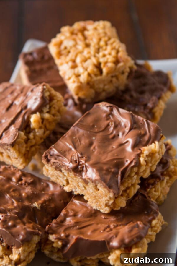 A stack of delicious Scotcheroos with peanut butter, rice krispies, butterscotch chips, and chocolate chips scotcheroos stacked on a white serving platter