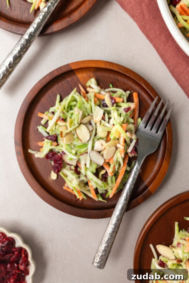 A small wooden salad plate holding a serving of fresh broccoli slaw, with a fork poised to enjoy, highlighting its appealing presentation.