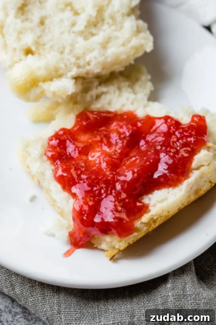 Surprisingly Easy 7 Up Biscuits 3 a close up of a flaky 7up biscuit with strawberry jam over the top!