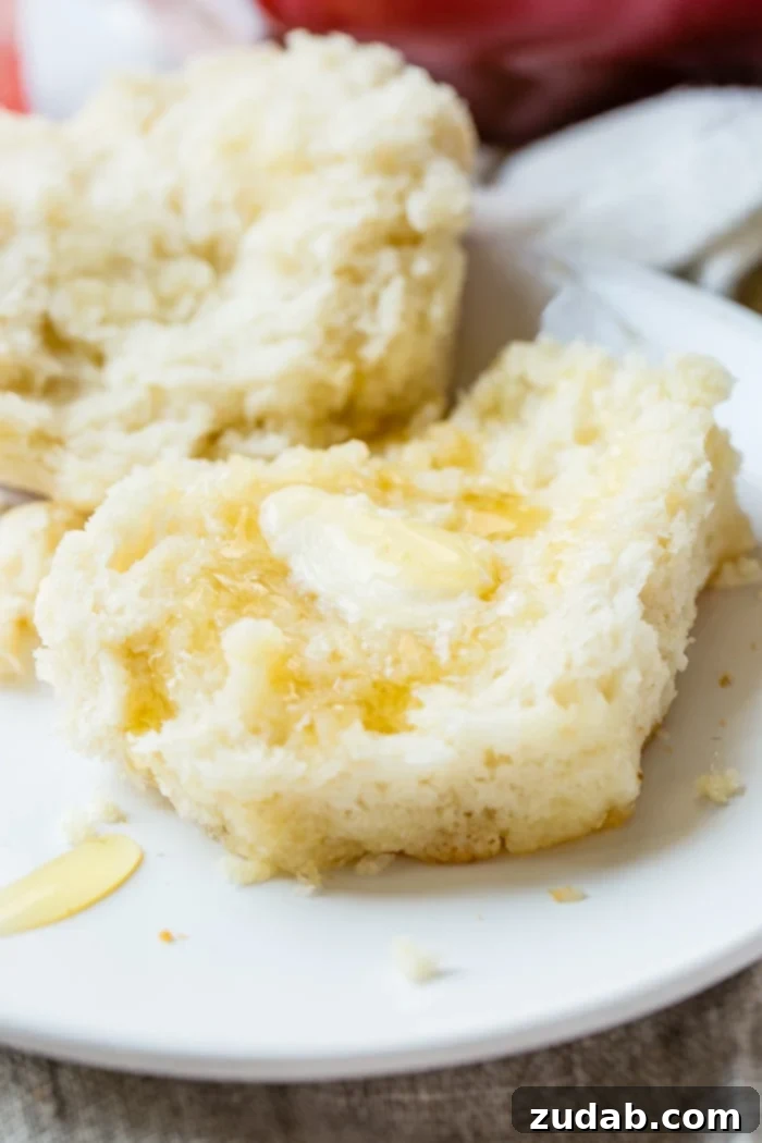 Surprisingly Easy 7 Up Biscuits 4 a close up of a flaky 7up biscuit with butter and a drizzle of honey over the top!