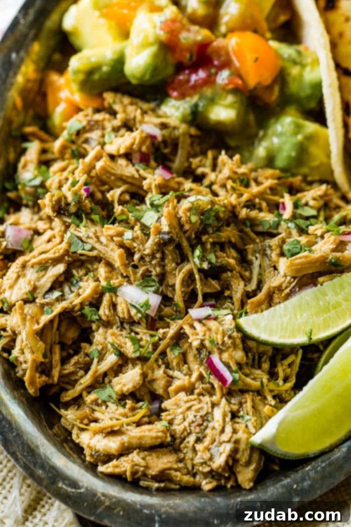 Creamy Instant Pot Poblano Chicken 3 A silver platter showcasing perfectly shredded Mexican Poblano Instant Pot Chicken, with fresh lime wedges on the side and soft tortillas blurred in the background, inviting a delicious meal.