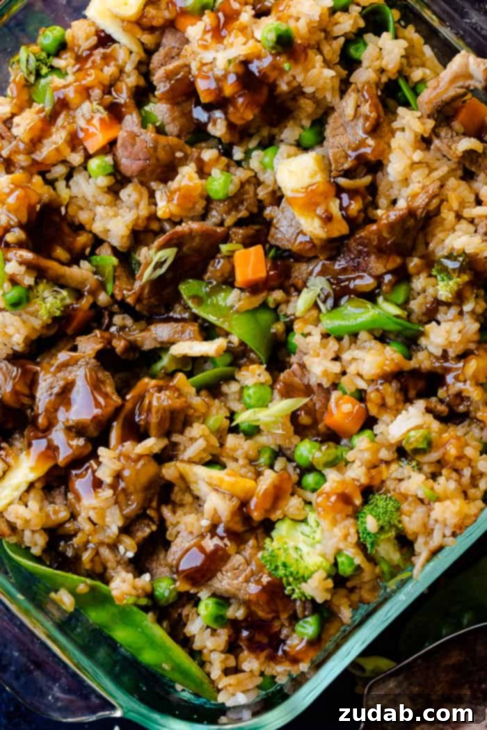 Teriyaki Beef Bake 2 a glass casserole dish with fried rice, carrots, peas, broccoli, snow peas, and teriyaki beef