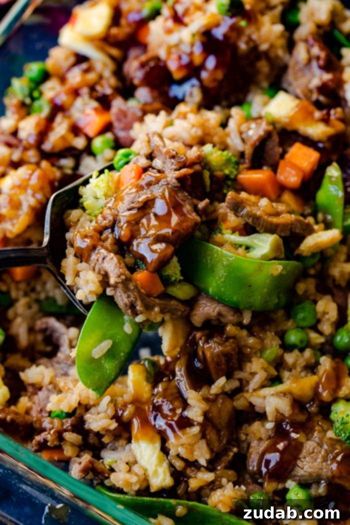 Teriyaki Beef Bake 3 a glass casserole dish with fried rice, carrots, peas, broccoli, snow peas, and teriyaki beef