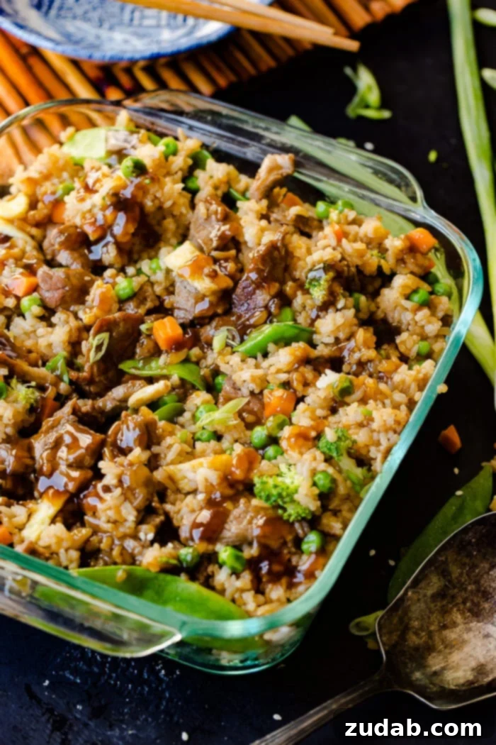 Teriyaki Beef Bake 4 a glass casserole dish with fried rice, carrots, peas, broccoli, snow peas, and teriyaki beef