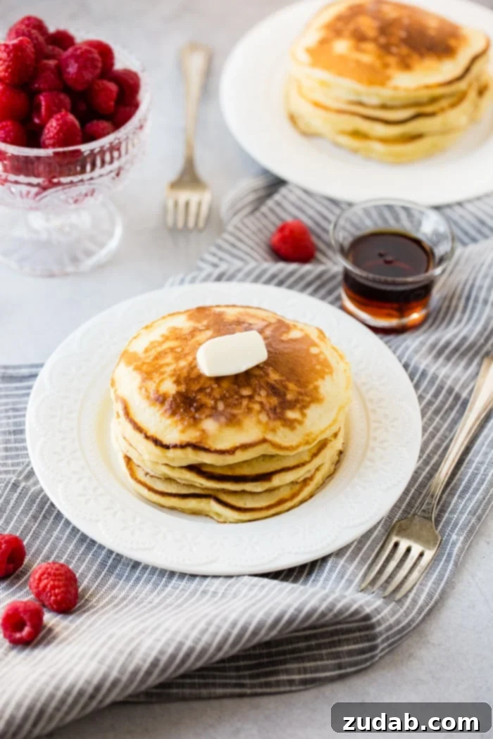 Cloud-Like Sour Cream Pancakes 3 A stack of fluffy banana sour cream pancakes with a little butter melting on top and a drizzle of syrup dripping down the side. Our recipe for melt in your mouth sour cream pancakes on a striped napkin with raspberries and maple syrup.