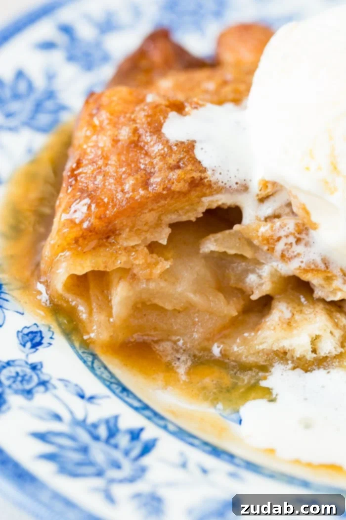 Sparkling Sprite Apple Dumplings 6 Two warm apple dumplings with caramel sauce and vanilla ice cream, served on a delicate blue china plate, ready to be enjoyed.