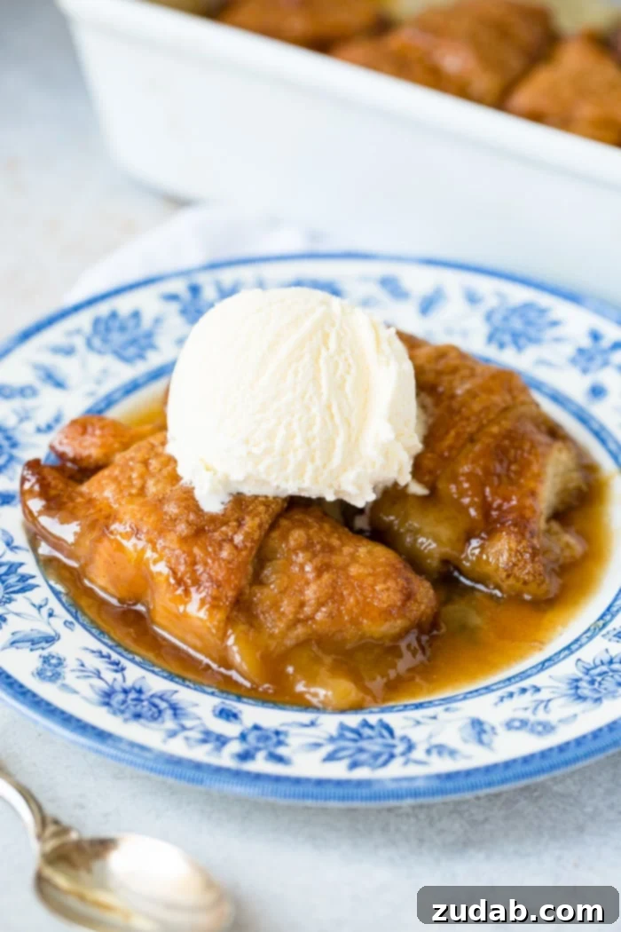 Sparkling Sprite Apple Dumplings 8 A blue china plate with two apple dumplings, caramel sauce, and a scoop of vanilla ice cream, styled for a delicious presentation.