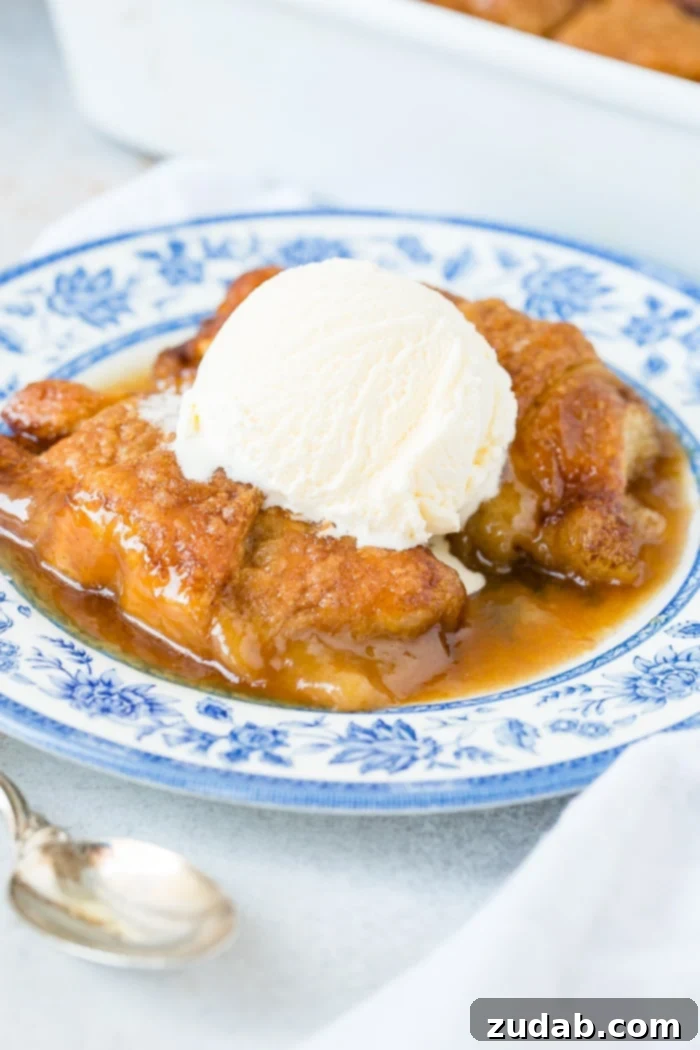 Sparkling Sprite Apple Dumplings 9 A blue china plate featuring two apple dumplings, drenched in caramel sauce and topped with melting vanilla ice cream.