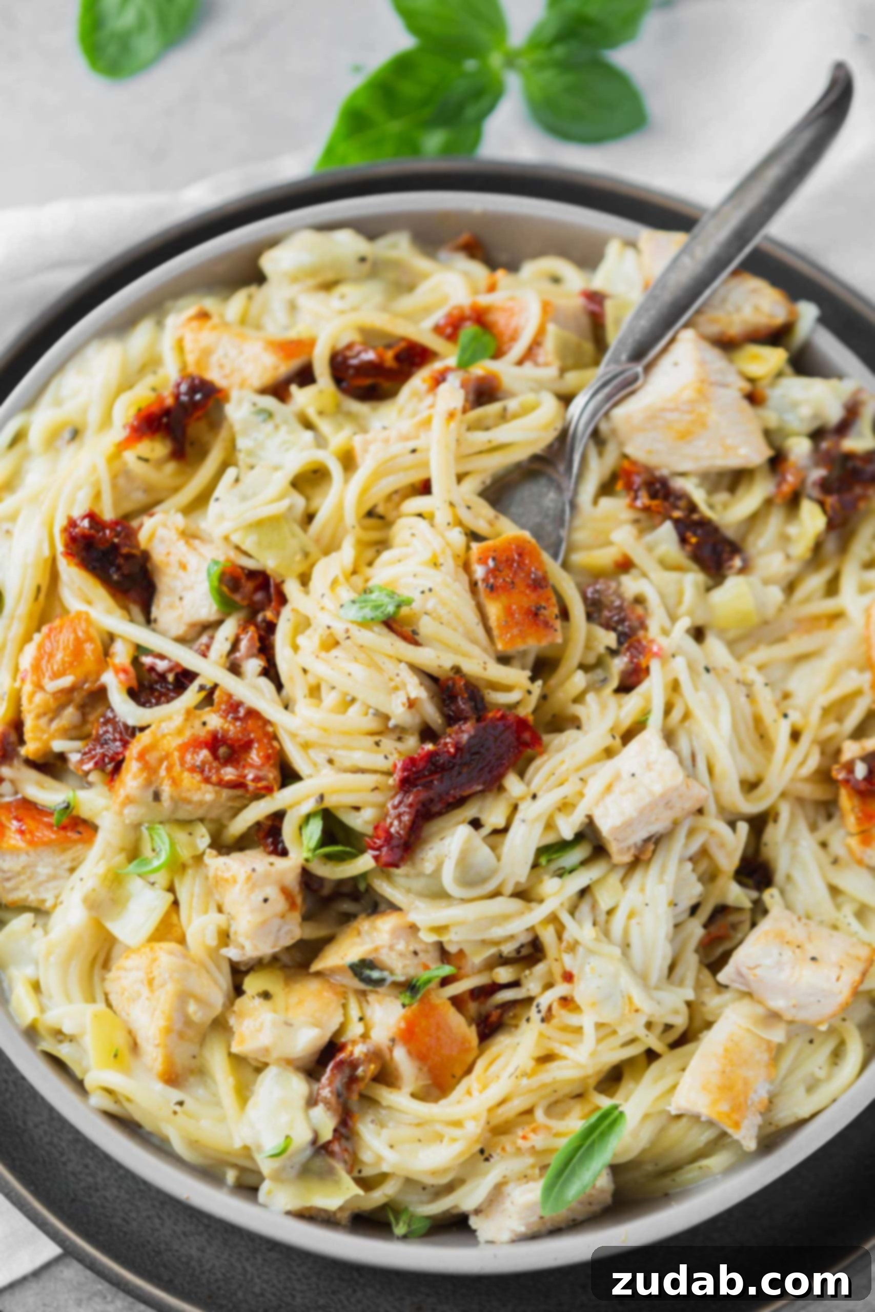 Creamy Chicken Artichoke Pasta a photo of creamy chicken artichoke pasta with a fork twirling up a bite.