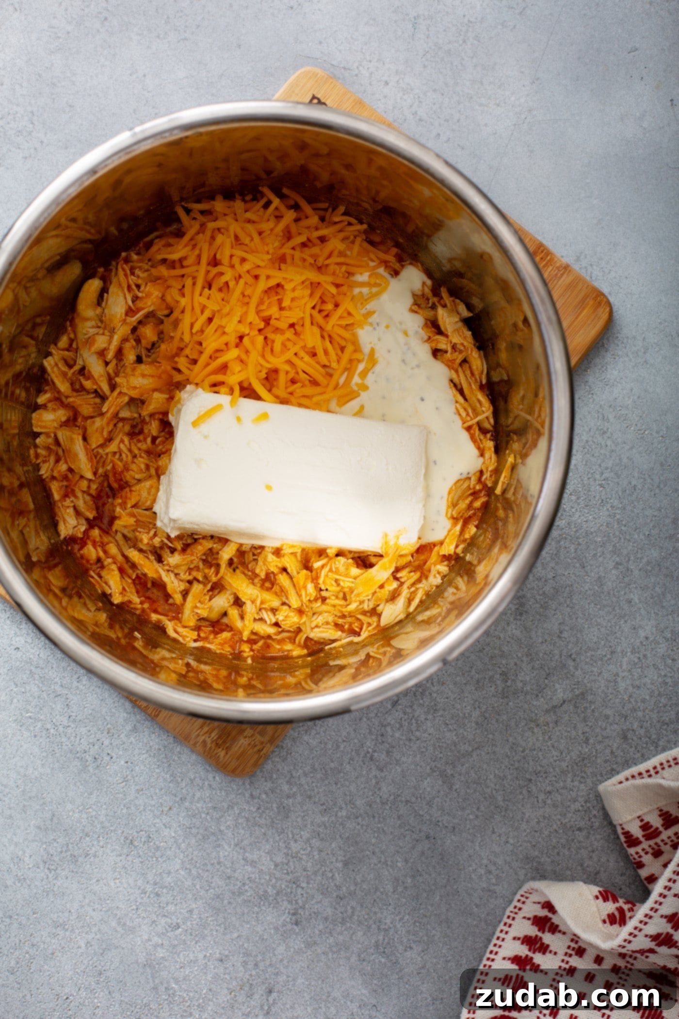 Instant Pot Buffalo Chicken Dip The pot of an instant pot with shredded chicken, cream cheese, shredded cheese and buffalo sauce.