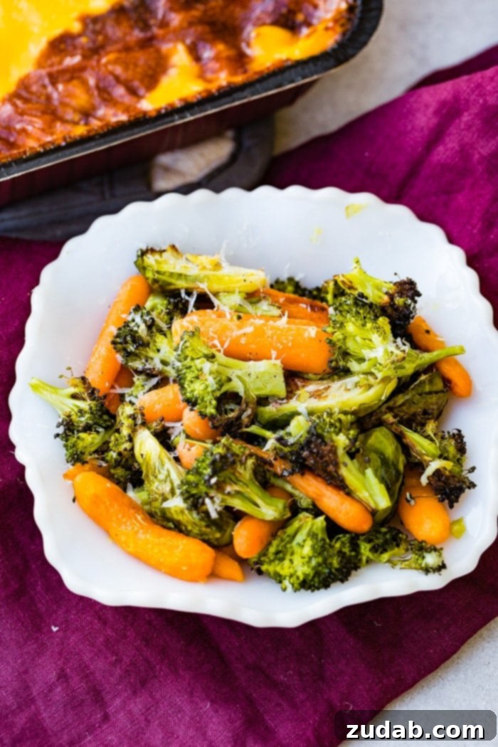 Effortless Garlic Roasted Vegetables 3 A vibrant white bowl filled with simple roasted garlic vegetables including tender carrots, crispy Brussels sprouts, and perfectly cooked broccoli, lightly dusted with Parmesan cheese.
