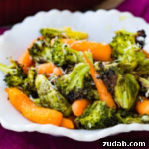 Effortless Garlic Roasted Vegetables 7 A white bowl showcasing simple roasted garlic veggies including carrots, Brussels sprouts and broccoli with a little parmesan cheese.