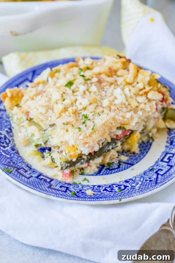 Golden Zucchini Corn Gratin 5 A beautifully presented slice of Cheesy Zucchini Corn Casserole on a blue plate, garnished with fresh herbs, showcasing the rich, golden-brown cracker topping and the vibrant layers within.