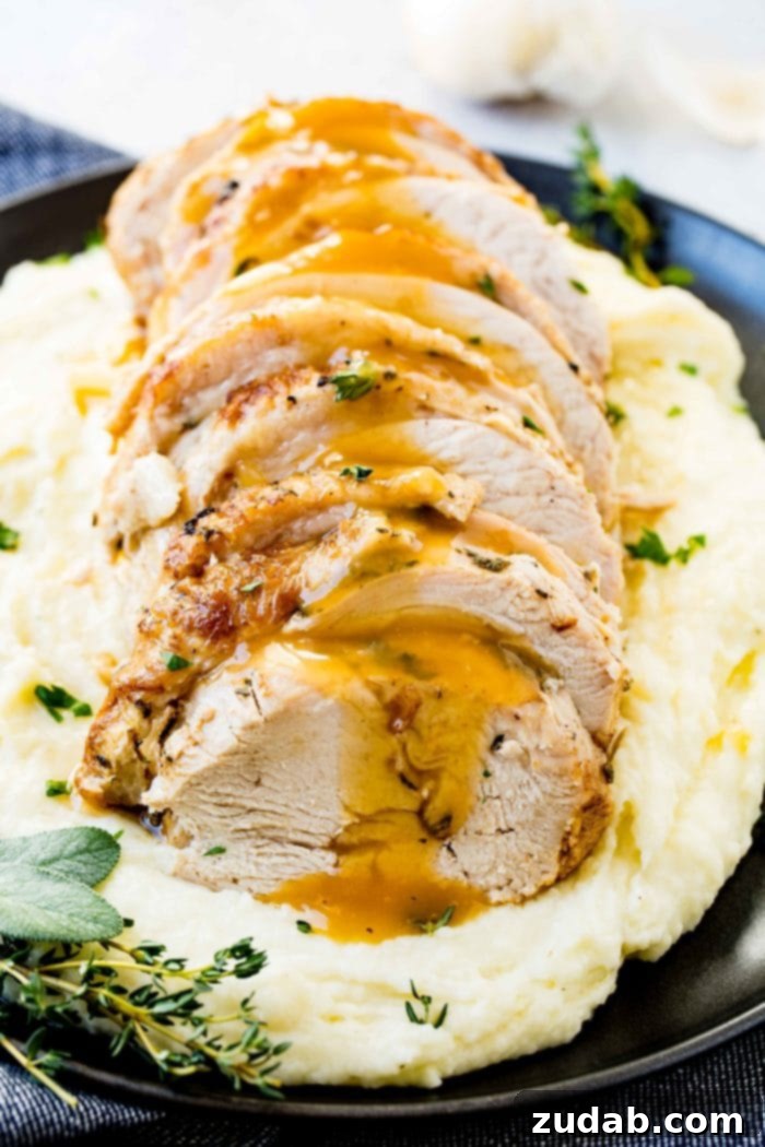 Award-Winning Instant Pot Turkey: The Ultimate Recipe 2 A beautifully sliced Instant Pot turkey breast, drizzled with rich gravy, and garnished with fresh herbs, served on a bed of creamy mashed potatoes on a sophisticated black plate.