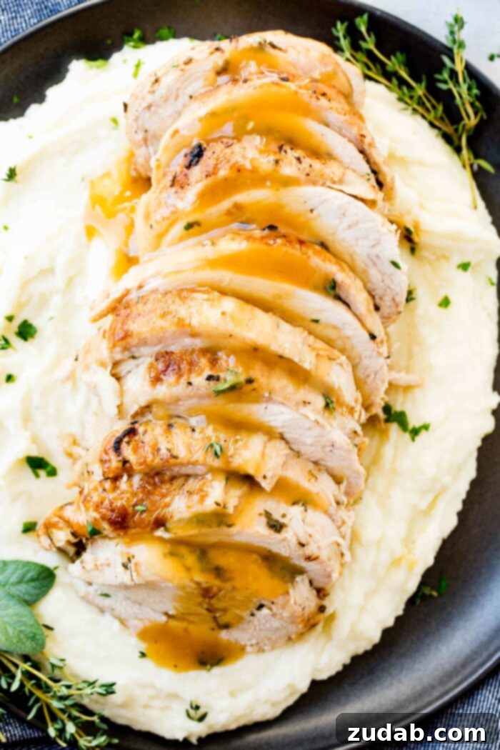 Award-Winning Instant Pot Turkey: The Ultimate Recipe 6 A tantalizing photo of perfectly sliced Instant Pot turkey breast, generously drizzled with rich, homemade gravy and adorned with fresh herbs, elegantly presented on a bed of creamy mashed potatoes on a sleek black plate.